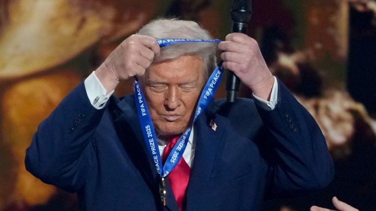 President Donald Trump puts on his FIFA Peace Prize during the draw for the 2026 soccer World Cup at the Kennedy Center in Washington