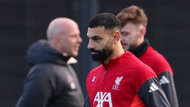 Mohamed Salah looks on during a Liverpool training session, with Arne Slot pictured in the background