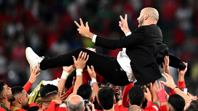 Morocco coach Walid Regragui is lifted up by his players after the World Cup win over Spain in Qatar