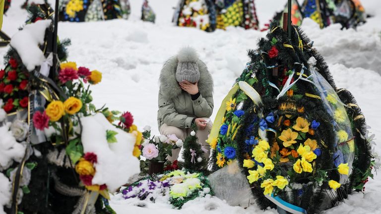 A woman reacts as she sits in front of a grave at a local cemetery in Chernihiv.
Pic: Reuters