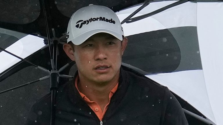 Collin Morikawa, right, walks with an umbrella in front of Akshay Bhatia toward the sixth tee at Pebble Beach Golf Links