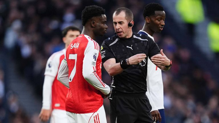 Peter Bankes speaks to Bukayo Saka while play is paused due to an issue with referee communications