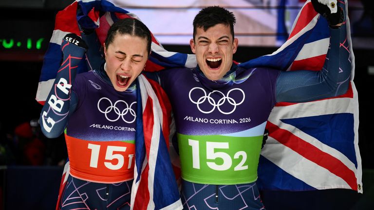 Britain's Tabitha Stoecker (L) and Britain's Matt Weston celebrate after winning the skeleton mixed team event at Cortina Sliding Centre during the Milano Cortina 2026 Winter Olympic Games in Cortina d'Ampezzo on February 15, 2026. (Photo by Marco BERTORELLO / AFP)