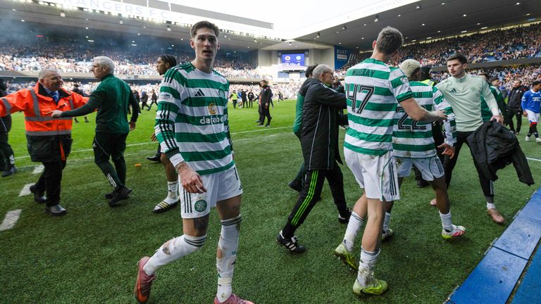 Celtic players are escorted off the pitch as fans storm onto the pitch at Ibrox