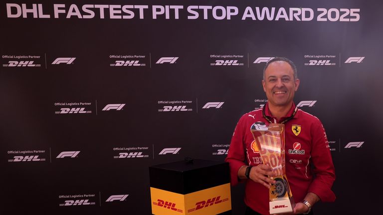 This image shows a Ferrari team member holding the trophy for the 2025 DHL Fastest Pit Stop Award