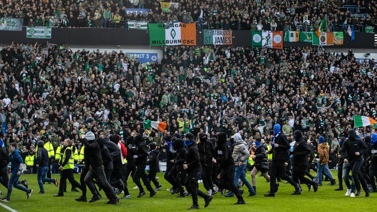 Police clash with fans as they storm the pitch during a Scottish Cup Quarter-Final match between Rangers and Celtic at Ibrox Stadium.