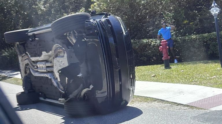 Golfer Tiger Woods stands by his overturned vehicle in Jupiter Island, Fla., on Friday, March 27, 2026. (AP Photo/Jason Oteri)