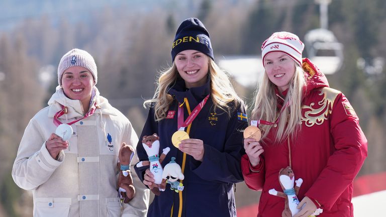 Silver medalist Aurelie Richard, of France, from left, gold medalist Ebba Aarsjoe, of Sweden, and bronze medalist Varvara Voronchikhina, of Russia, pose on the podium of the alpine skiing women's downhill standing competition at the 2026 Winter Paralympics, in Cortina d'Ampezzo, Italy, Saturday, March 7, 2026. (AP Photo/Emilio Morenatti)