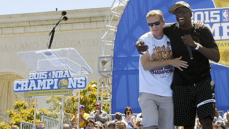 Draymond Green van de Golden State Warriors brengt hoofdcoach Steve Kerr naar de voorkant van het podium terwijl hij spreekt tijdens de kampioensparade in 2015