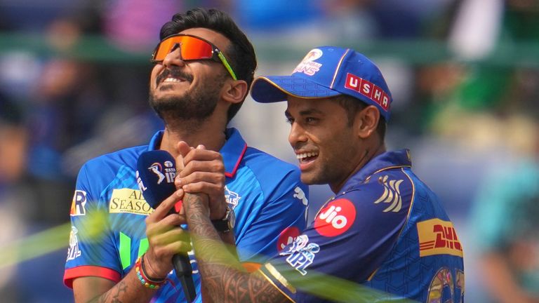 Mumbai Indians' stand-in captain Suryakumar Yadav, right, playfully holds the hand of Delhi Capitals' captain Axar Patel (AP)