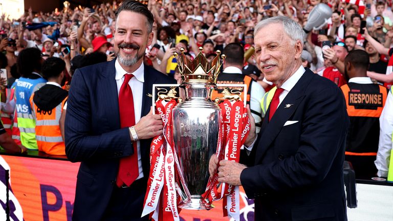 Arsenal co-chair Josh Kroenke holds the Premier League trophy with his father, Stan