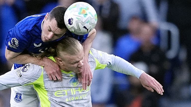 Michael Keane wins a header ahead of Erling Haaland