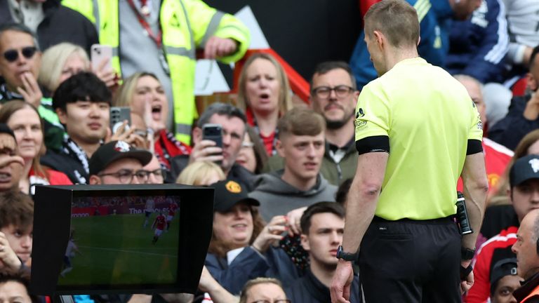English referee Michael Salisbury consults the pitch-side monitor after being told by the VAR (Video Assistant Referee) that there was a handball in the build-up to a goal by Manchester United's Brazilian striker #10 Matheus Cunha, he still gave the goal, during the English Premier League football match between Manchester United and Nottingham Forest at Old Trafford in Manchester, north west England, on May 17, 2026. (Photo by Darren Staples / AFP) / RESTRICTED TO EDITORIAL USE. No use with unauthorized audio, video, data, fixture lists, club/league logos or 'live' services. Online in-match use limited to 120 images. An additional 40 images may be used in extra time. No video emulation. Social media in-match use limited to 120 images. An additional 40 images may be used in extra time. No use in betting publications, games or single club/league/player publications. / 