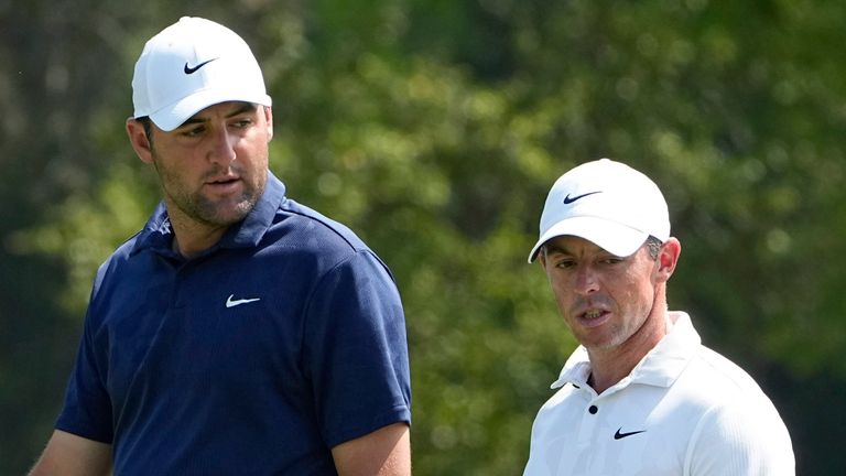Scottie Scheffler, left, and Rory McIlroy, of Northern Ireland, center, walk up the fairway