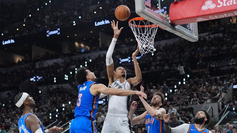 O atacante do San Antonio Spurs, Victor Wembanyama, sobe para uma cesta contra o guarda do Oklahoma City Thunder, Shai Gilgeous-Alexander e outros