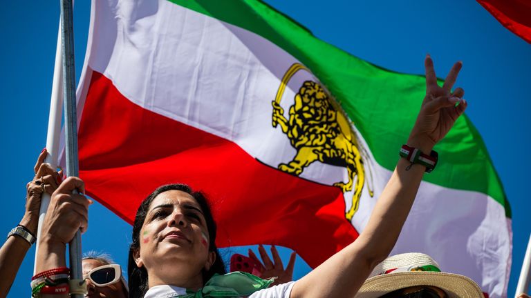 A woman holds up a peace sign during a protest in reaction to FIFA's ban of Iran's pre-revolutionary flag inside World Cup stadiums Sunday, June 7, 2026, in Inglewood, Calif. (AP Photo/Benjamin Hanson)