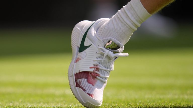O sapato direito do italiano Jannik Sinner mostra uma mancha vermelha durante a partida individual masculina contra Miomir Kecmanovic, da Sérvia, no Wimbledon Ten