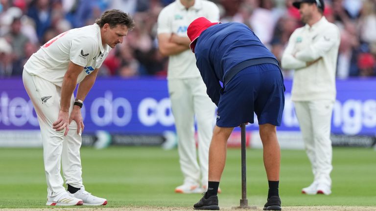New Zealand's Nathan Smith looks on as a groundsman flattens the pitch on day two