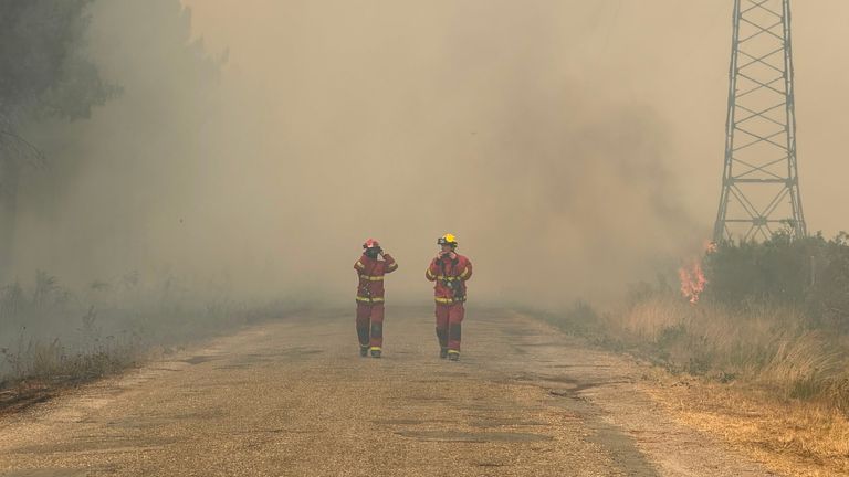 Two firefighters walk through smoke as wildfires continue to rage on. Pic: Sky 