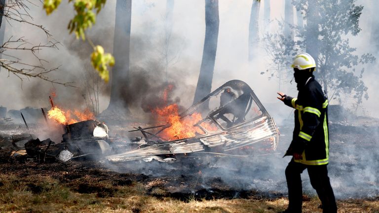A firefighter walks next to the burning remains of a camper van during a wildfire in Lege-Cap-Ferret in the Gironde department, amid worsening drought conditions following a heatwave and water shortages across much of France, July 24, 2026. REUTERS/S
