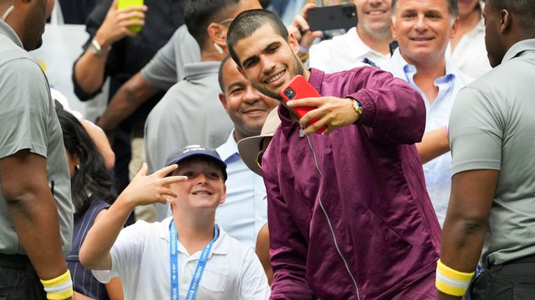 Carlos Alcaraz, of Spain, takes a selfie with fans after defeating Novak Djokovic, of Serbia, in the men's singles semifinals of the U.S. Open tennis championships, Friday, Sept. 5, 2025, in New York. (AP Photo/Kirsty Wigglesworth)