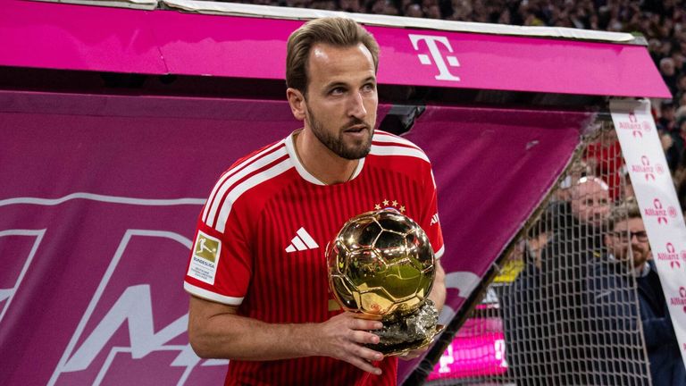 Harry Kane brings the Ballon d'Or trophy  onto the pitch ahead of Der Klassiker